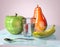 3d illustration of green apple pear banana spoon and glass with water creative still life on glass table in pink room with day