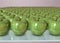 3d illustration of many green apples creative still life on glass table in pink room with day light imitation