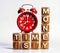 3d illustration of wooden cubes crossword text word TIME IS MONEY with alarm clock