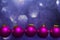 3d render of beautiful flying dark pink Christmas baubles on a purple bokeh lights background