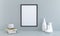 3D render of a blank black picture frame on a gray wall with copy space near books and vases