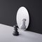 3d render, chess game piece, black pawn stands in front of the round mirror with white reflection. Contradiction concept.