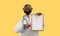 3d render. Happy doctor african cartoon character shows clipboard with blank paper. Clip art isolated on yellow background.