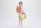 3d render. Modern lady holding shopping bags and gift box. Cheerful cartoon character