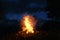 3d rendering of big bonfire with sparks and particles in front of foggy mountain and conifer trees