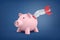 3d rendering of big pink piggy bank stands with a small retro rocket broken and stuck inside its side.