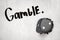 3d rendering of black casino dice breaking white wall with `Gamble` sign on white background
