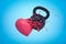 3d rendering of black kettlebell hitting and breaking pink heart on light blue background.