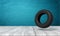 3d rendering of black tractor wheel on white wooden floor and dark turquoise background