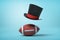 3d rendering of a brown gridiron football and a black tophat floating in air above the ball on light blue background.