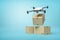 3d rendering of camera drone delivering cardboard box on top of two other boxes standing on light blue gradient