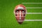 3d rendering of cartoon smiley american football ball wearing helmet on green field background