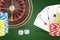 3d rendering of a casino roulette, cards, chips and dice closely arranged on a green background.