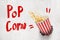 3d rendering of concrete wall with title `Pop Corn` and pop corn bucket that has broken hole in the wall.