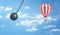 3d rendering of a giant wrecking ball dangerously swings near a striped hot air balloon on a clouded sky background.