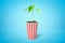 3d rendering of green sprout growing in popcorn bucket on blue background