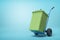 3d rendering of green trash can on blue hand truck which is standing in half-turn on light-blue background with copy