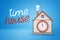 3d rendering of house with smoking chimney and big clock-face on wall and title `time house` on blue background.
