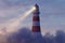 3d rendering of an illuminated lighthouse over fluffy clouds