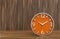 3d rendering. modern orange victory time clock on wooden floor and copy space wall background