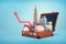 3d rendering of a open retro suitcase holding a piggy bank, skyscrapers, safe box, credit card and an upwards arrow.