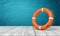 3d rendering of orange lifebuoy standing on wooden surface near blue wall.