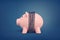 3d rendering of a pink piggy bank bound in chains in the middle of its body on a blue background.