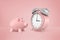 3d rendering of pink piggy bank stands near huge pink retro alarm clock on a pink background.