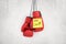 3d rendering of red boxing gloves with yellow `Good luck` note on white wall background