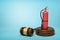 3d rendering of red fire extinguisher standing on sounding block with gavel lying beside on light-blue background with