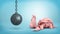 3d rendering of a resting wrecking ball on a chain hangs near a cracked piggy bank on blue background.