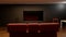 3D rendering of room with blank black plasma TV in focus, hifi speakers, with red sofa in the middle. Home cinema advertisment