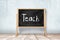3d rendering of school blackboard with `TEACH` chalk sign on white wooden floor and white wall background