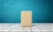 3d rendering of a single closed cement bag vertically placed on a wooden desk on blue background.