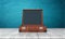 3d rendering of a single retro brown suitcase with its lid open standing on a wooden desk.