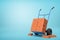 3d rendering of stack of red perforated bricks on blue hand truck with several bricks on ground on light-blue background