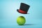 3d rendering of tennis ball and black tophat floating in air above it on light blue background.