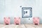 3d rendering of three cute piggy banks face forward standing near a wall with a drawing of a closed safe on it.