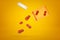 3d rendering of TNT dynamite sticks falling out of plastic pills jar on yellow background