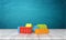 3d rendering of a toy building blocks lying in a colorful pile over a wooden desk on a blue background.