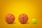 3d rendering of two basketballs and one tennis ball in row on amber background.