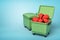 3d rendering of two green trash cans, front can open and full of broken valentine hearts, on light-blue background.