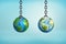 3d rendering of a two wrecking balls hanging on metal chains one with a detailed Earth drawing and another with a sloppy