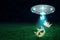 3d rendering of UFO in air at night with golden crowns falling out from its open hatch onto green grass.