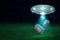 3d rendering of UFO with open hatch under night sky dropping three retro radio sets onto green field.