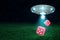 3d rendering of UFO under night sky dropping three red dice from its open hatch down onto green field.