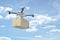 3d rendering of white drone carrying cardboard box on blue sky background