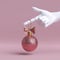 3d white mannequin hand holding rose gold Christmas tree ball ornament decorated with bow, isolated on pink background