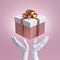 3d white mannequin hands holding wrapped gift box with golden ribbon bow. Seasonal festive clip art, isolated on pink background.