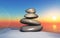 3D zen landscape with a stack of pebbles in sand against a sunset sky